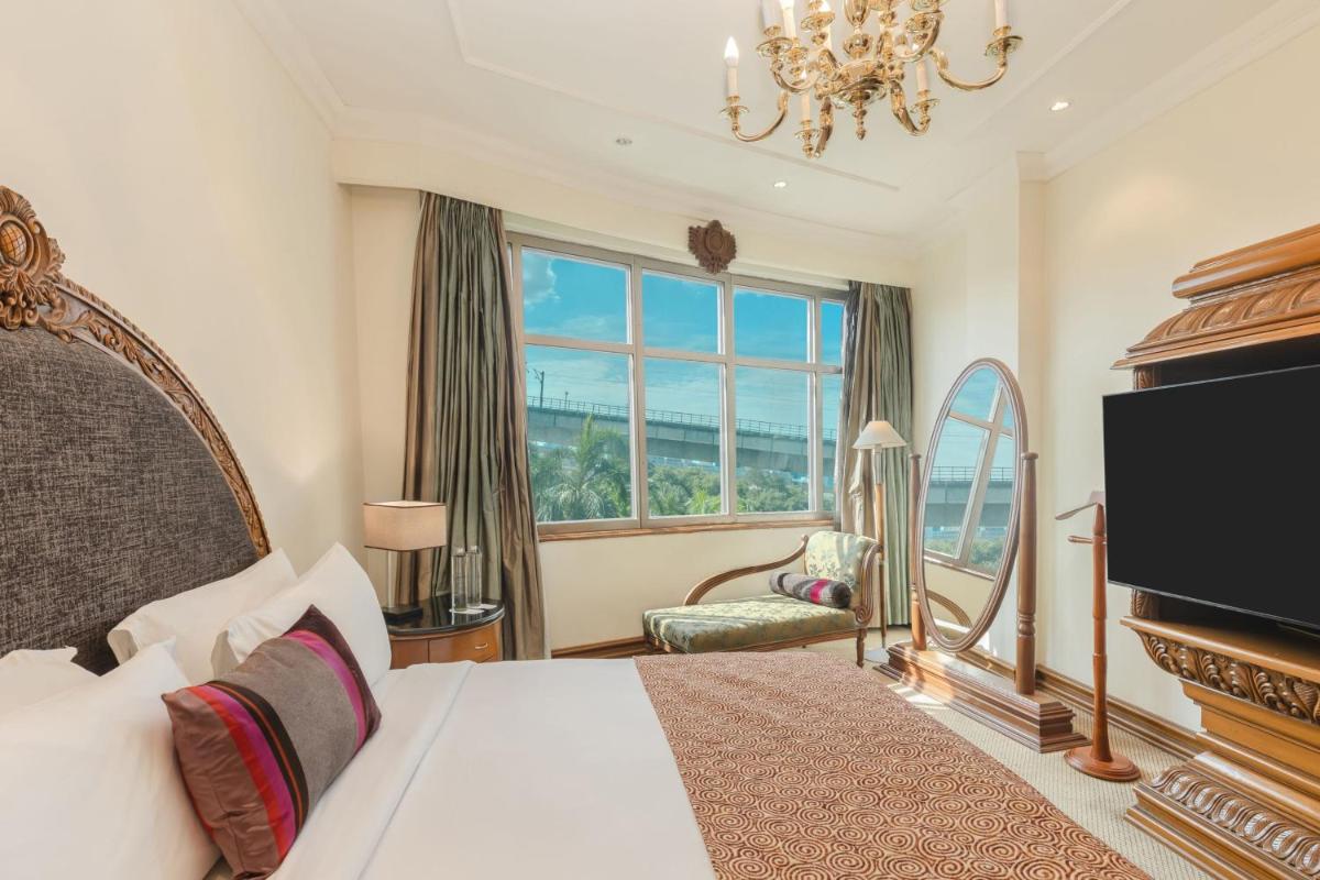 a bedroom with a bed and a large window at Le Royal Meridien Chennai in Chennai