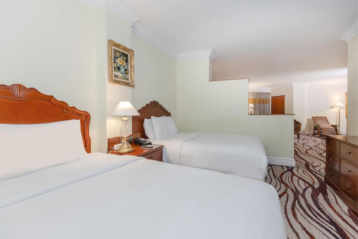 a hotel room with two beds and a mirror at Le Royal Meridien Chennai in Chennai