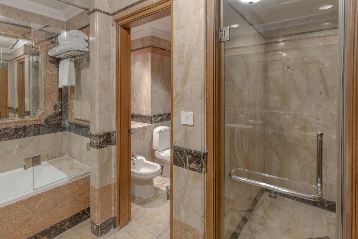 a bathroom with a shower and a toilet and a glass door at Le Royal Meridien Chennai in Chennai