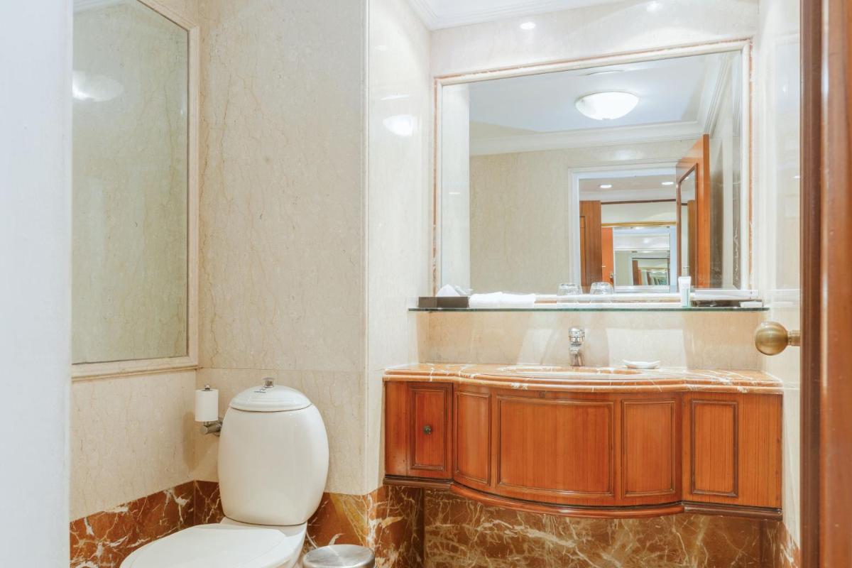a bathroom with a toilet and a large mirror at Le Royal Meridien Chennai in Chennai