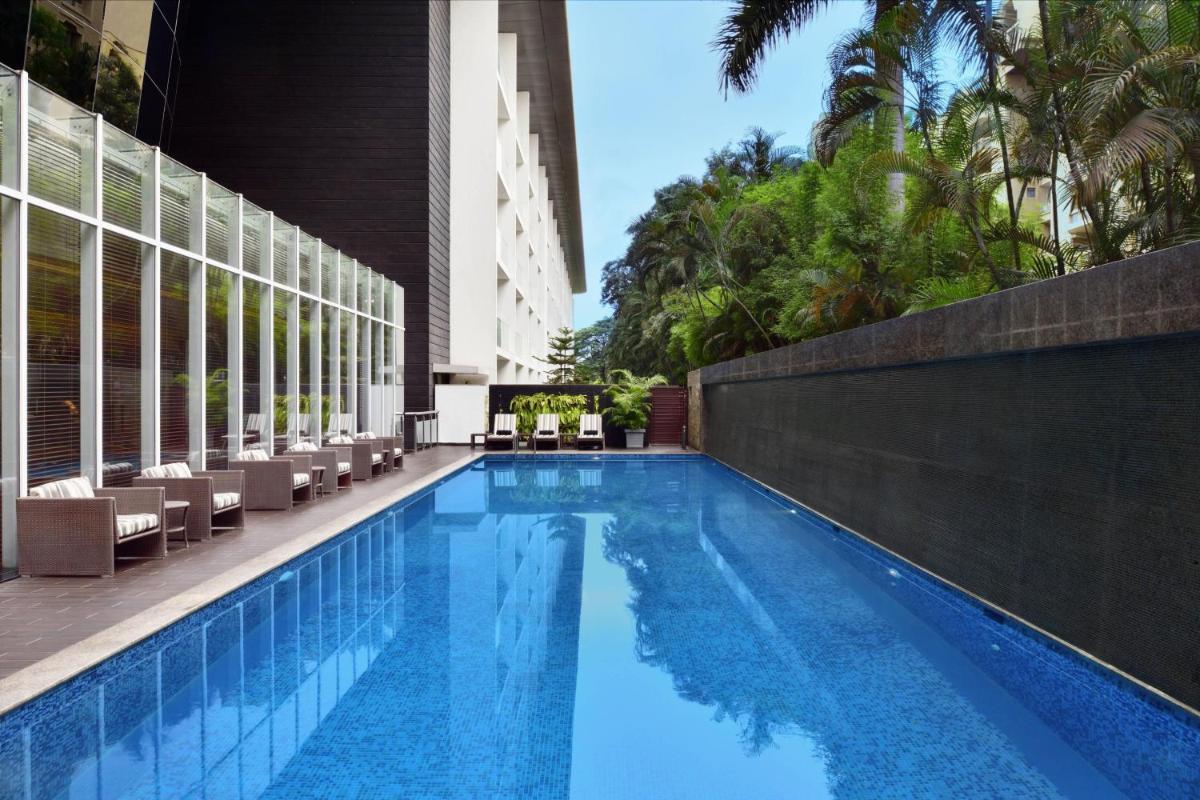 a swimming pool at a hotel with chairs and trees at Marriott Suites Pune in Pune