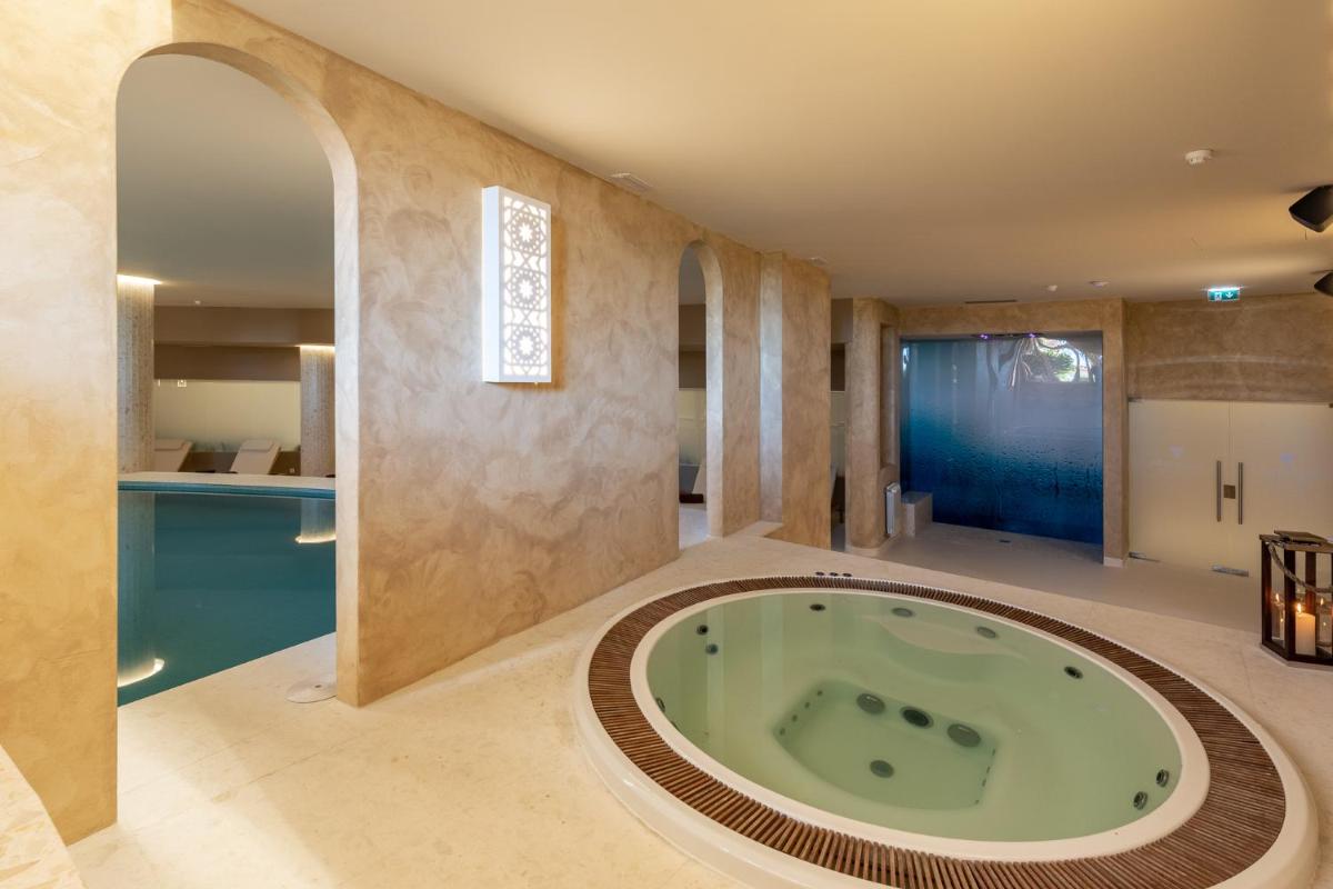 uma casa de banho com uma grande banheira no meio de um quarto em Belavista Da Luz - Wellness & Lifestyle Hotel na Praia da Luz