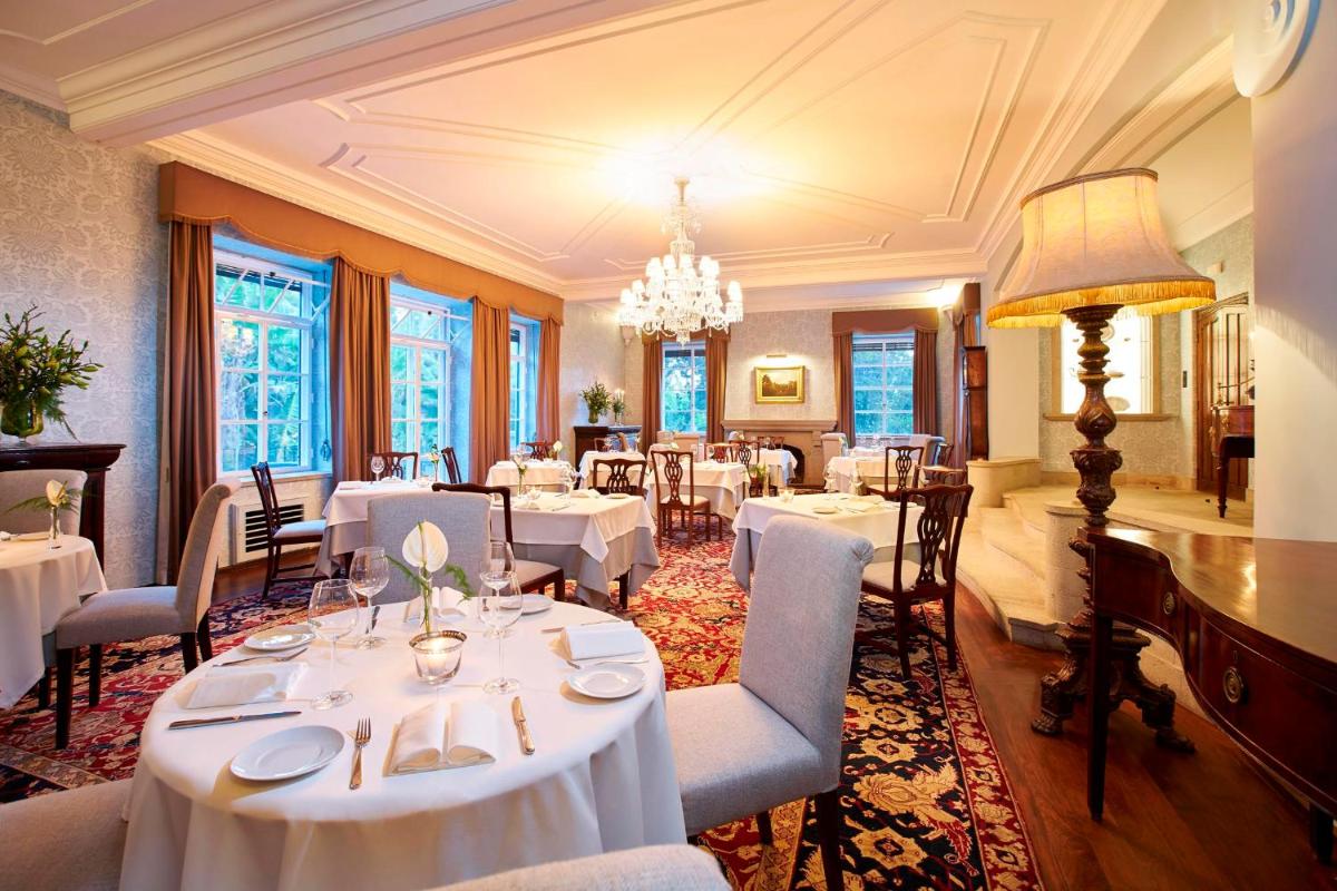 um restaurante com mesas e cadeiras brancas e um lustre em Quinta da Casa Branca - Small Luxury Hotels of the World no Funchal