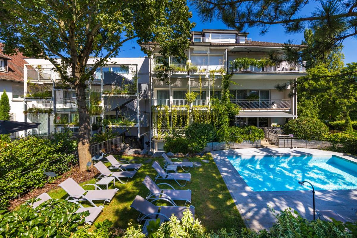 un immeuble d'appartements avec piscine et chaises longues dans l'établissement Hôtel Villa La Florangerie - SPA & Piscine, à Strasbourg