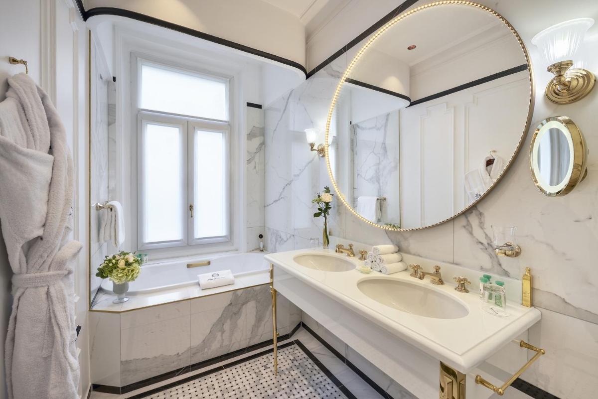 La salle de bains est pourvue d'un grand miroir et d'un lavabo. dans l'établissement Hotel Westminster, à Paris