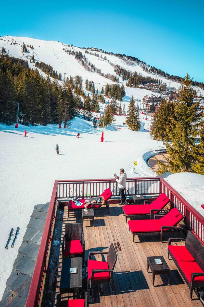 une terrasse avec des chaises rouges et une piste de ski dans l'établissement Hotel Carlina, à Courchevel 37 autres photos