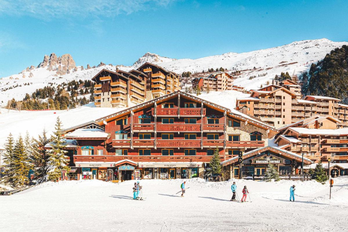 un groupe de personnes debout dans la neige devant un lodge de ski dans l'établissement Hotel Mont Vallon, à Méribel