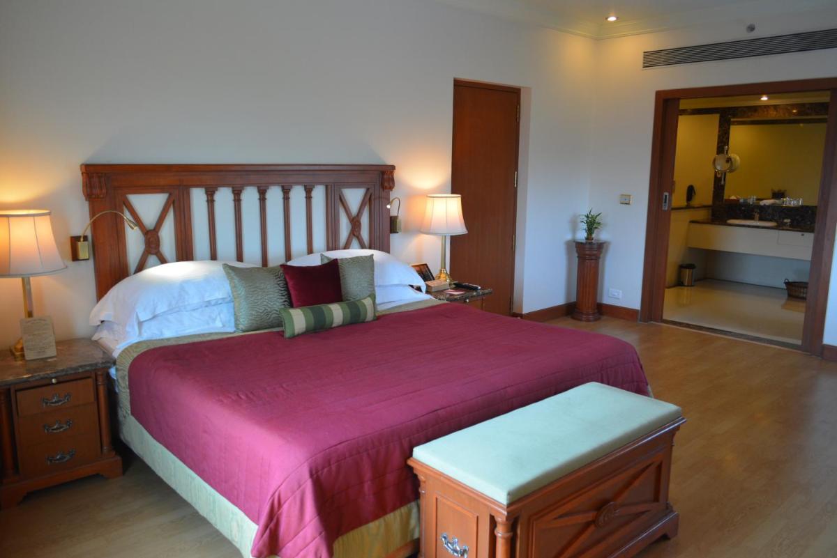 a bedroom with a large bed with a wooden headboard at The Orchid Hotel Mumbai Vile Parle in Mumbai