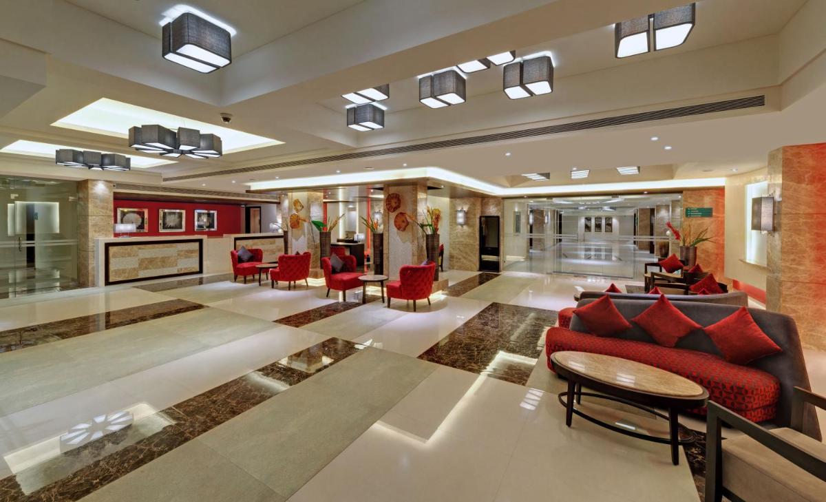 a lobby with a red couch and red chairs at The Fern Kadamba Hotel And Spa in Old Goa