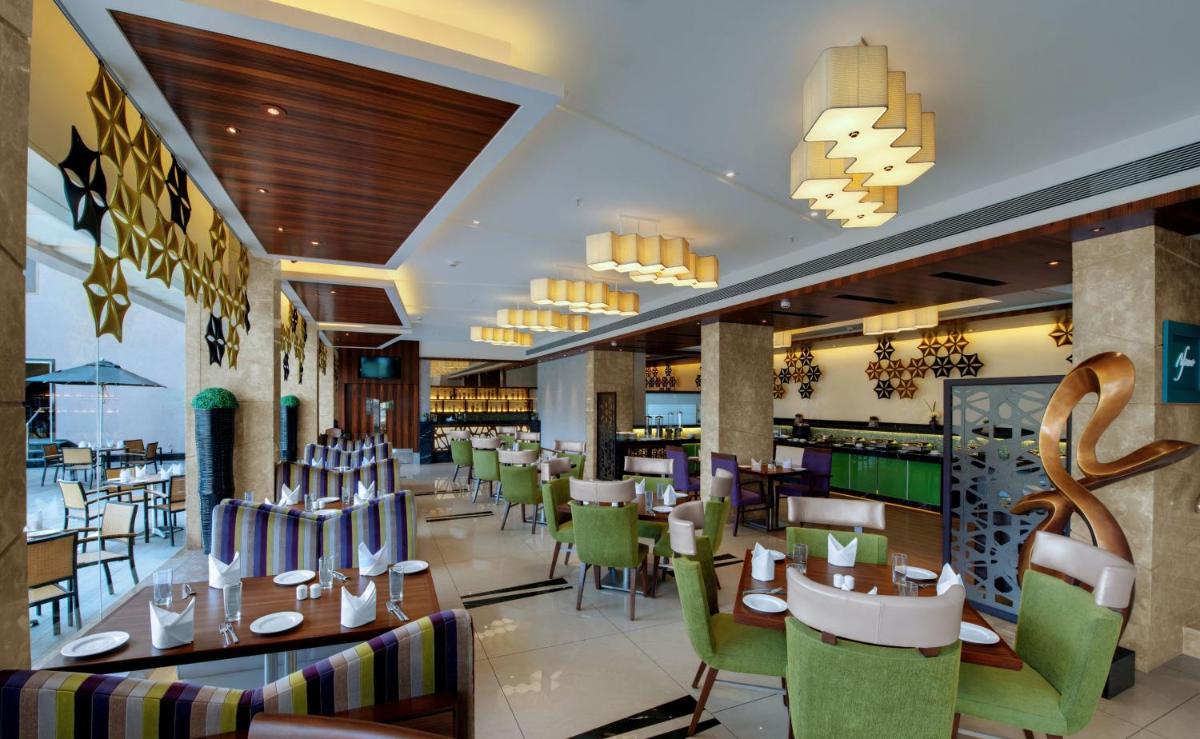 a restaurant with tables and chairs and a bar at The Fern Kadamba Hotel And Spa in Old Goa a restaurant with tables and chairs and a bar at The Fern Kadamba Hotel And Spa in Old Goa