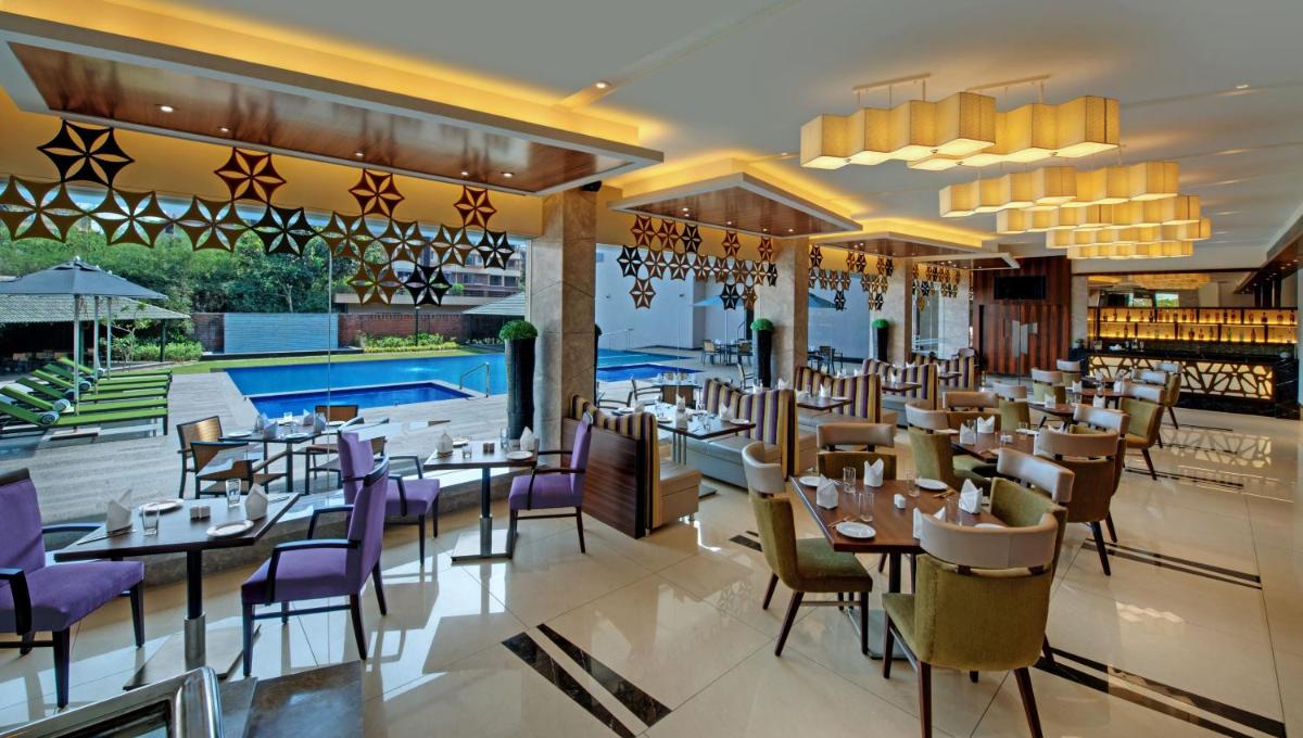 a restaurant with tables and chairs and a pool at The Fern Kadamba Hotel And Spa in Old Goa