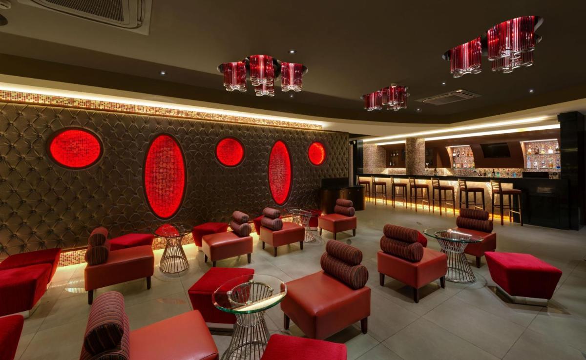 a restaurant with red chairs and tables and a bar at The Fern Kadamba Hotel And Spa in Old Goa