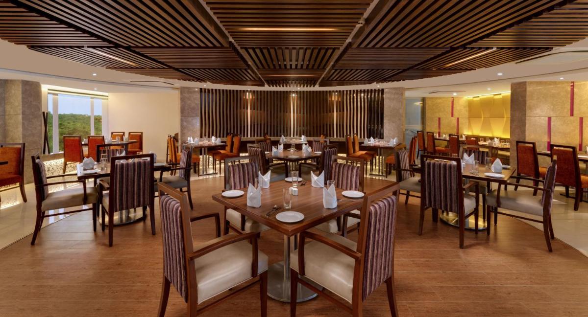 a restaurant with tables and chairs in a room at The Fern Kadamba Hotel And Spa in Old Goa