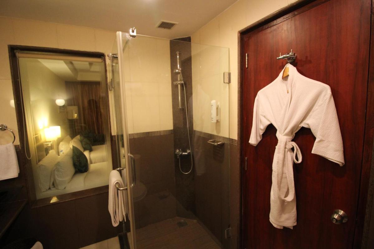 a bathroom with a shower and a robe hanging on a door at Fortune Select JP Cosmos, Bengaluru - Member ITC Hotels' Group in Bengaluru