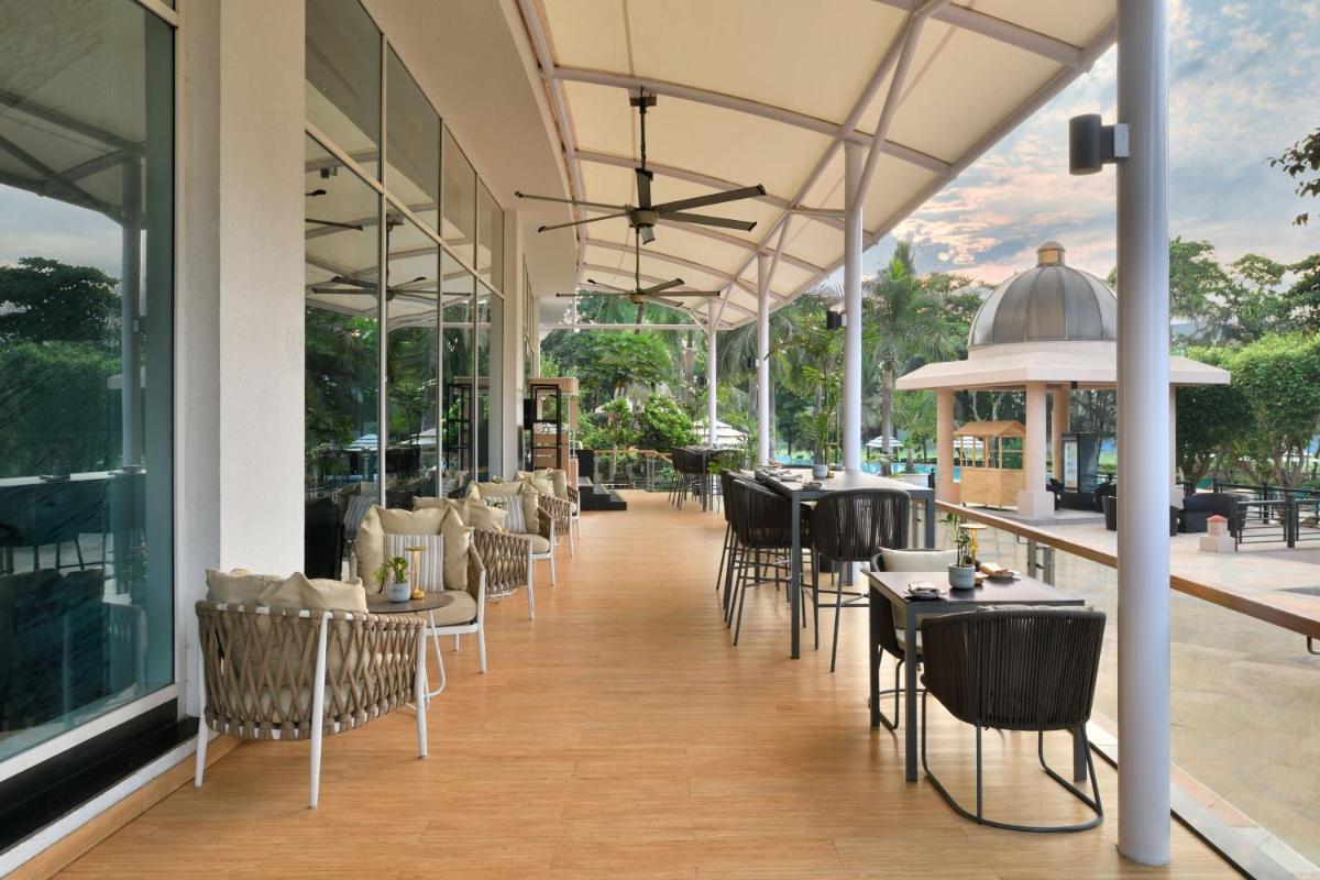 a restaurant with tables and chairs on a balcony at The Westin Mumbai Powai Lake in Mumbai