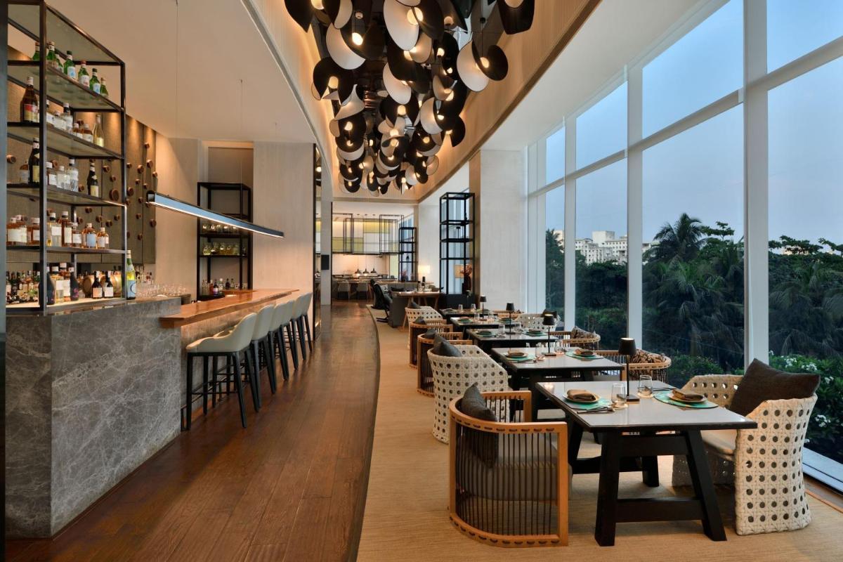 a restaurant with tables and chairs and large windows at The Westin Mumbai Powai Lake in Mumbai