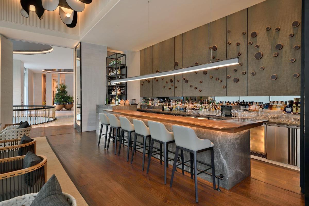 a bar in a restaurant with white bar stools at The Westin Mumbai Powai Lake in Mumbai