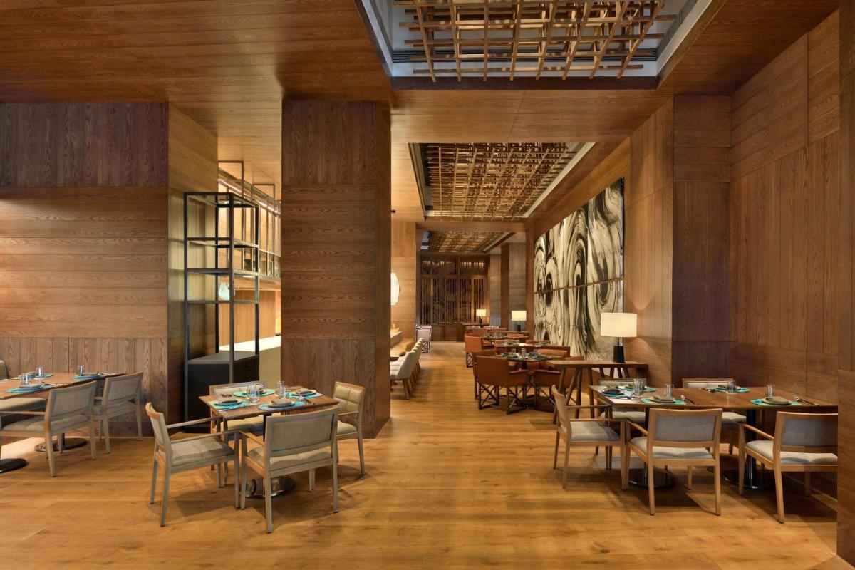 a dining room with tables and chairs and a painting at The Westin Mumbai Powai Lake in Mumbai