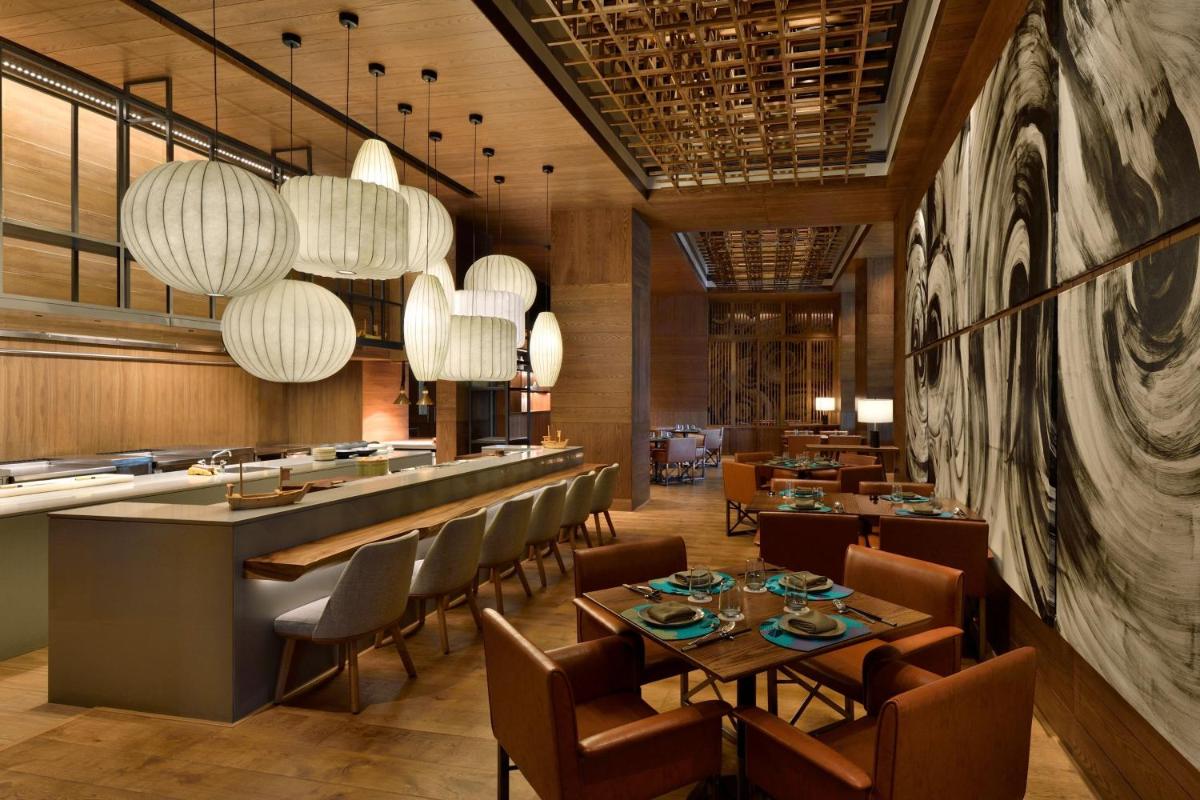 a restaurant with tables and chairs and a bar at The Westin Mumbai Powai Lake in Mumbai