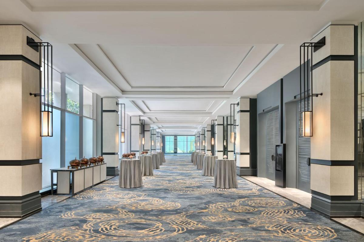 a hallway with a row of tables and a row of windows at The Westin Mumbai Powai Lake in Mumbai