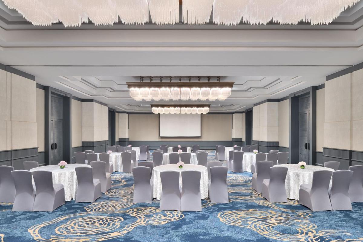 a ballroom with tables and chairs in a room with chandeliers at The Westin Mumbai Powai Lake in Mumbai