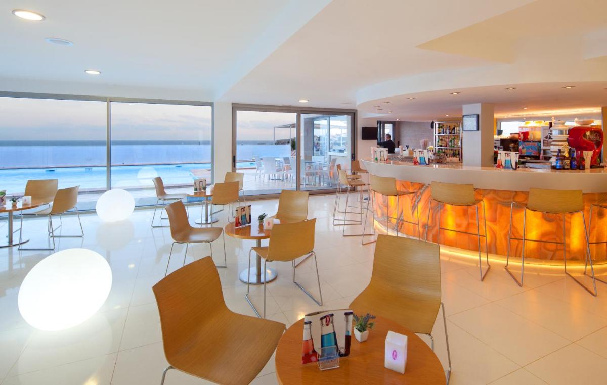 un restaurante con un bar con vistas al océano en JS Cape Colom - Adults Only, en Portocolom