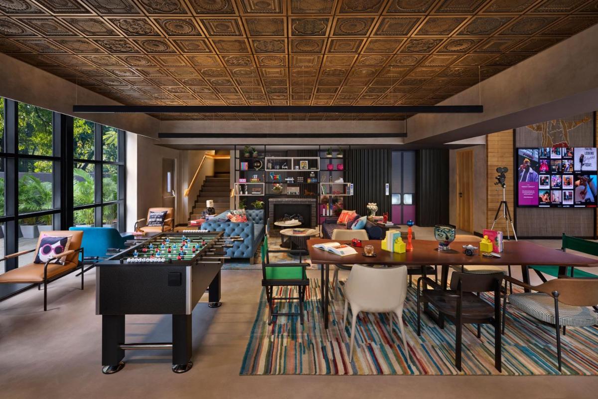 a room with tables and chairs and a living room at Moxy Mumbai Andheri West in Mumbai