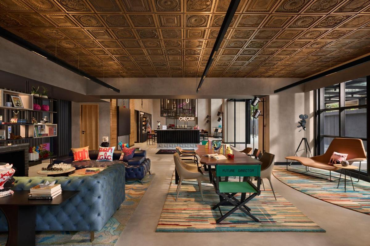 a living room with a couch and tables and chairs at Moxy Mumbai Andheri West in Mumbai