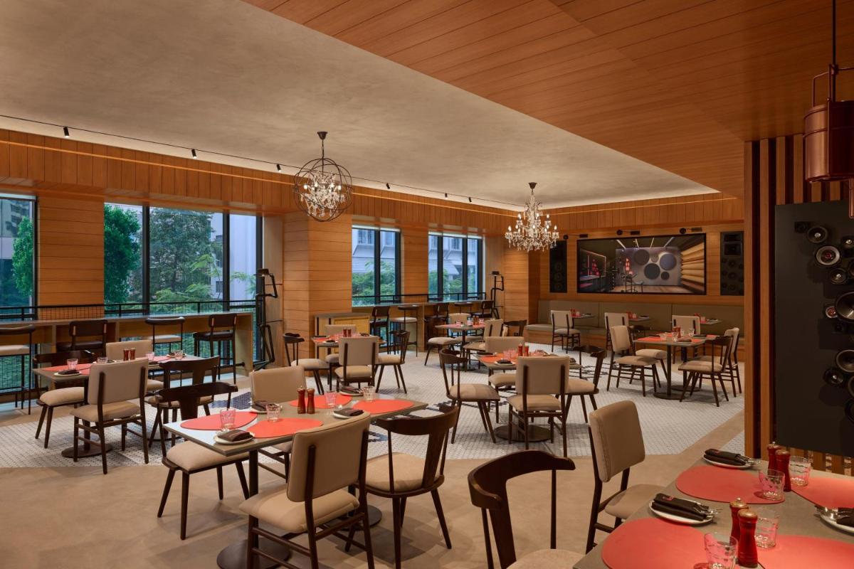 a dining room with tables and chairs and windows at Moxy Mumbai Andheri West in Mumbai
