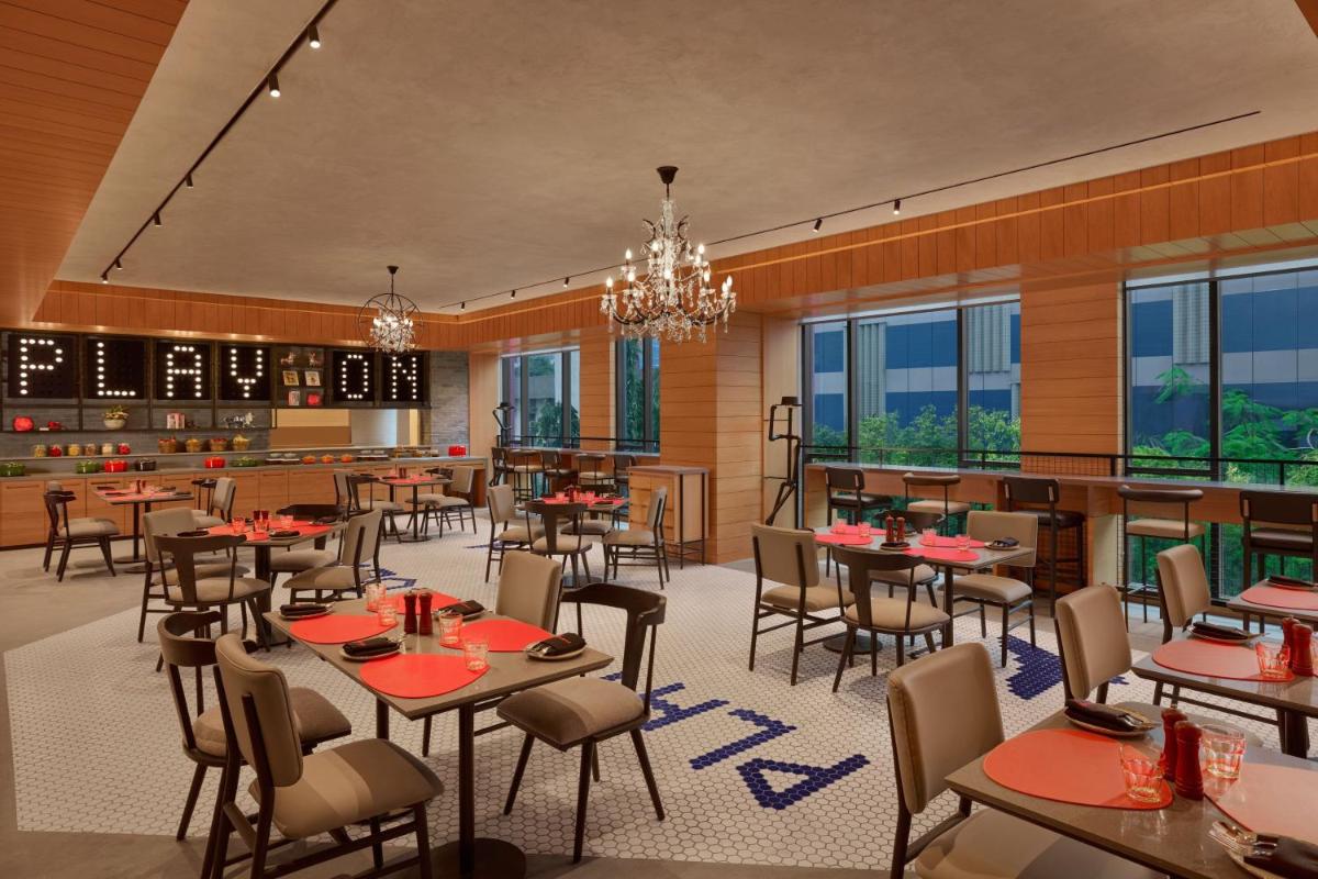 a restaurant with tables and chairs and windows at Moxy Mumbai Andheri West in Mumbai