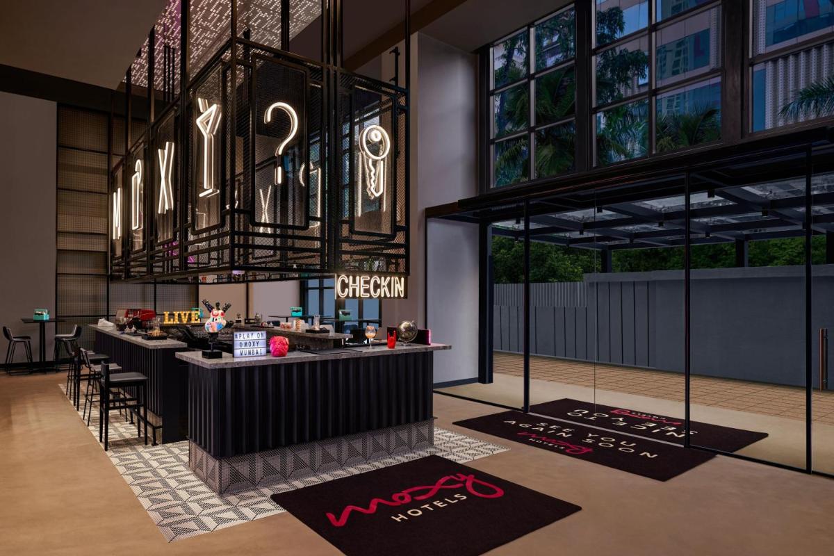 a restaurant with a bar with a chandelier at Moxy Mumbai Andheri West in Mumbai