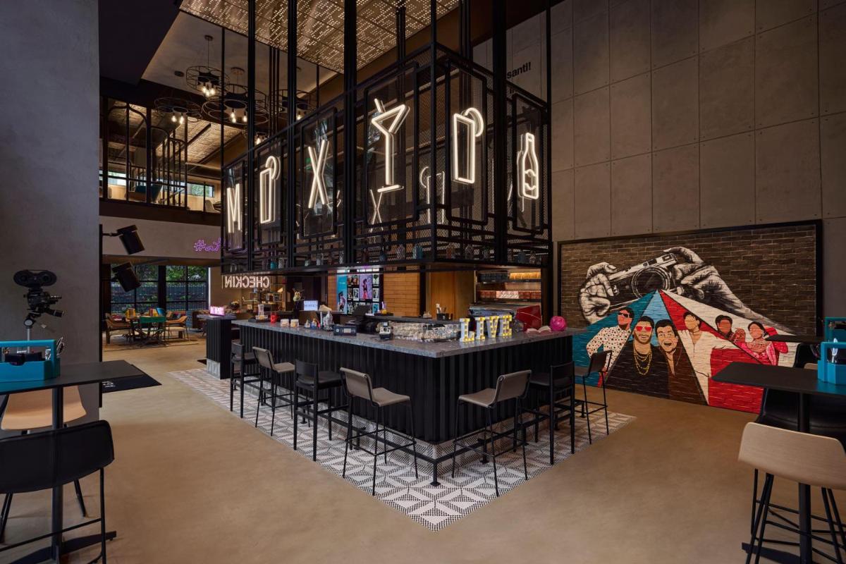 a restaurant with a bar in the middle of a room at Moxy Mumbai Andheri West in Mumbai