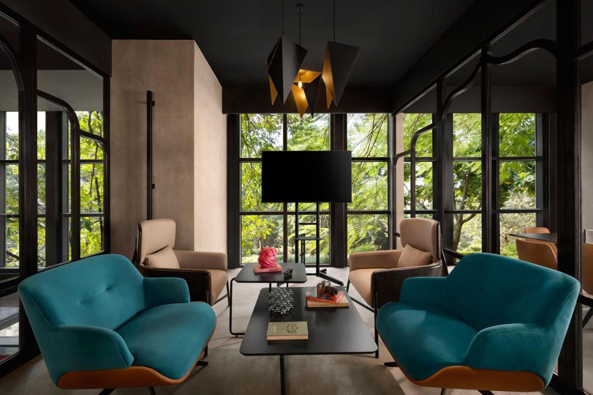 a living room with blue chairs and a tv at Moxy Mumbai Andheri West in Mumbai