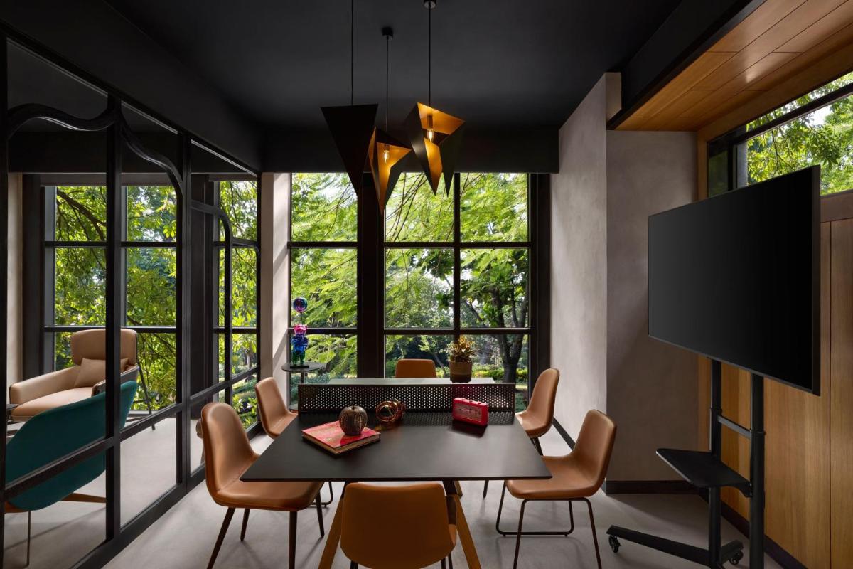 a dining room with a table and chairs and windows at Moxy Mumbai Andheri West in Mumbai