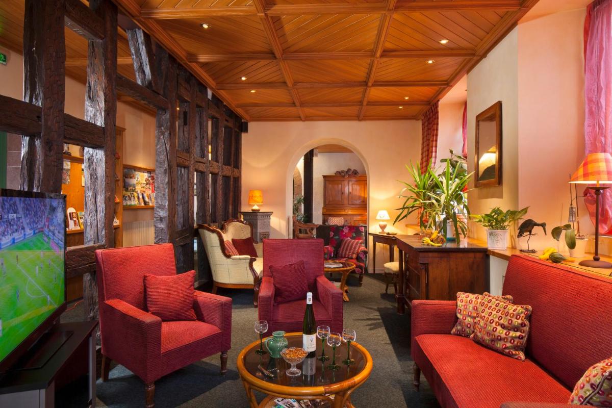 Il comprend un salon doté de fauteuils rouges et d'une télévision à écran plat. dans l'établissement Logis Hôtel de la Tour, à Ribeauvillé