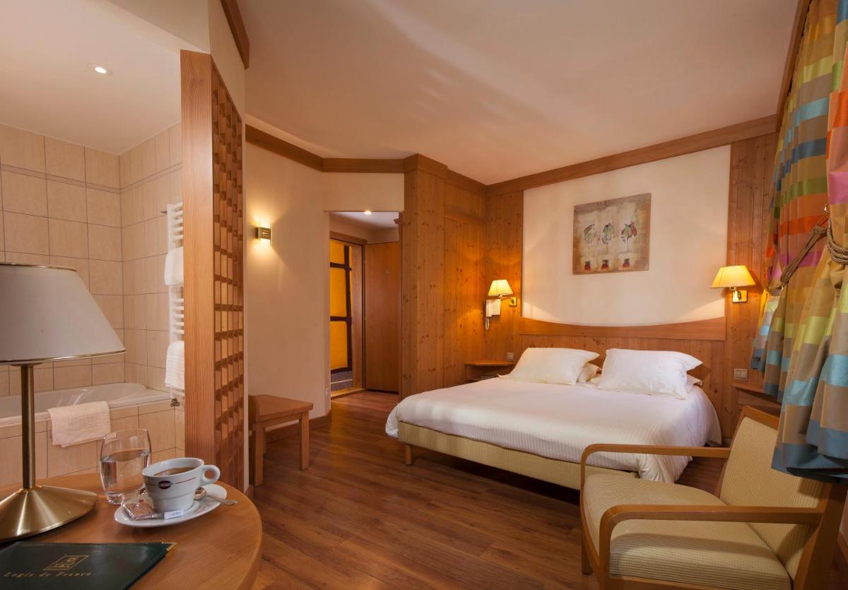 une chambre d'hôtel avec un lit et une table dans l'établissement Logis Hôtel de la Tour, à Ribeauvillé 66 autres photos