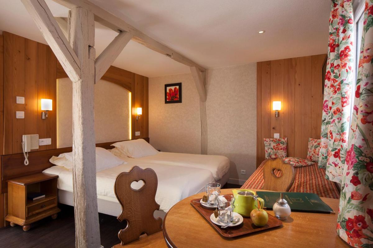 une chambre d'hôtel avec un lit et une table dans l'établissement Logis Hôtel de la Tour, à Ribeauvillé