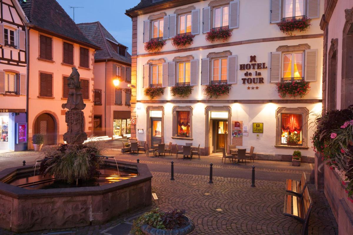 une place de ville avec une fontaine en face d'un bâtiment dans l'établissement Logis Hôtel de la Tour, à Ribeauvillé