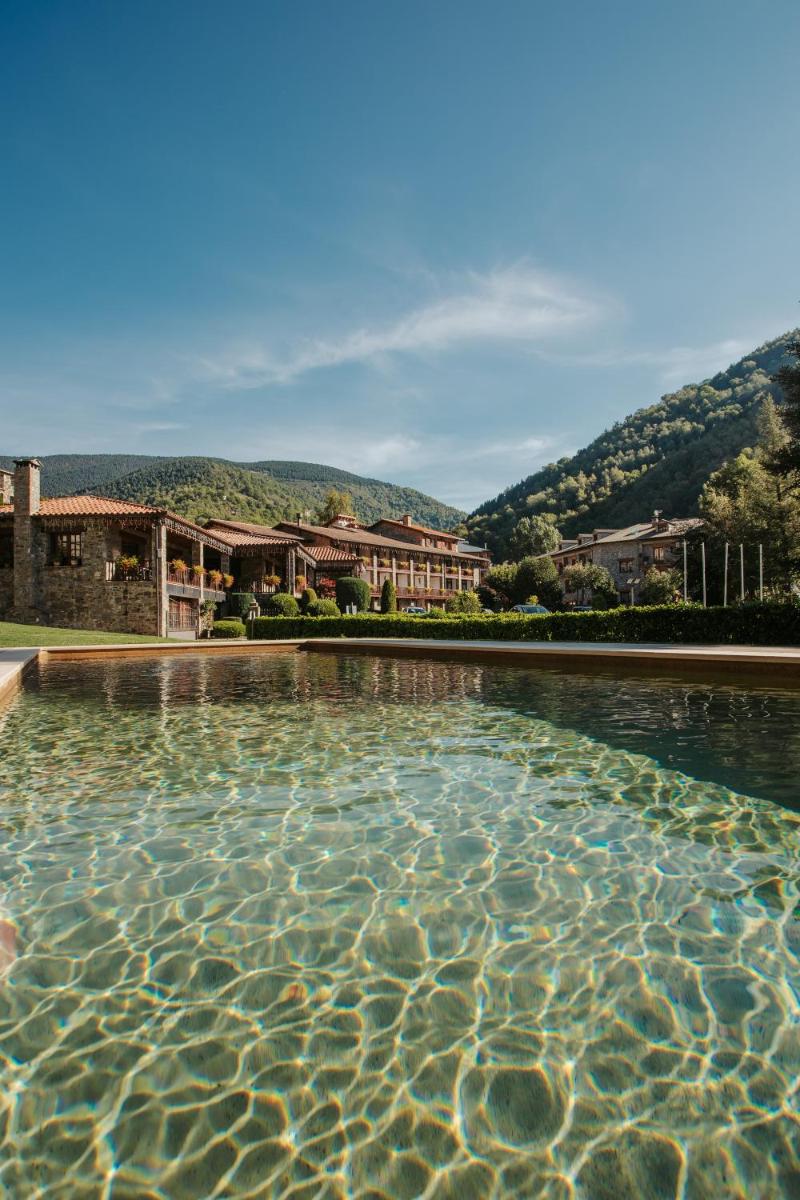 una piscina en un complejo con montañas en el fondo en Hotel La Coma, en Setcases