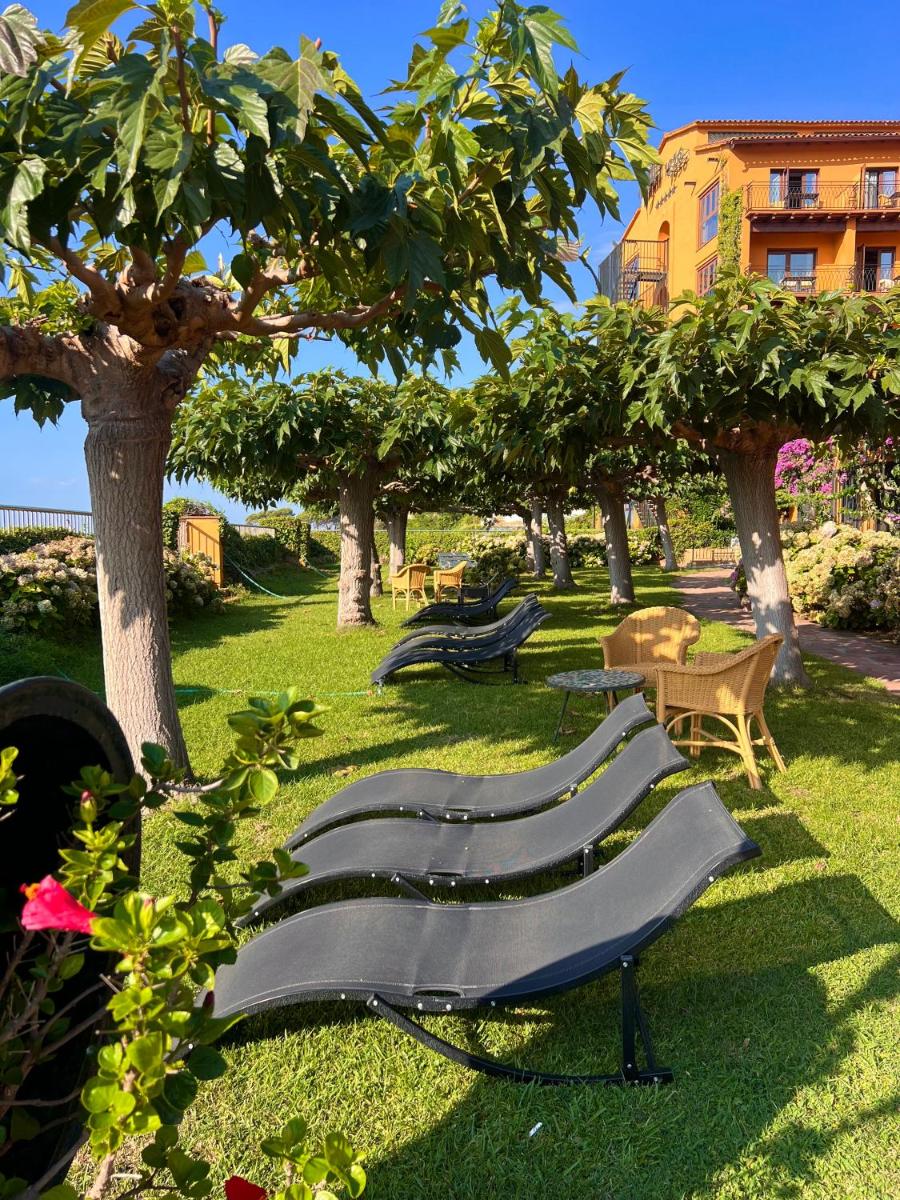 una fila de bancos en un parque con árboles en Rigat Park & Spa Hotel - Adults Recommended, en Lloret de Mar