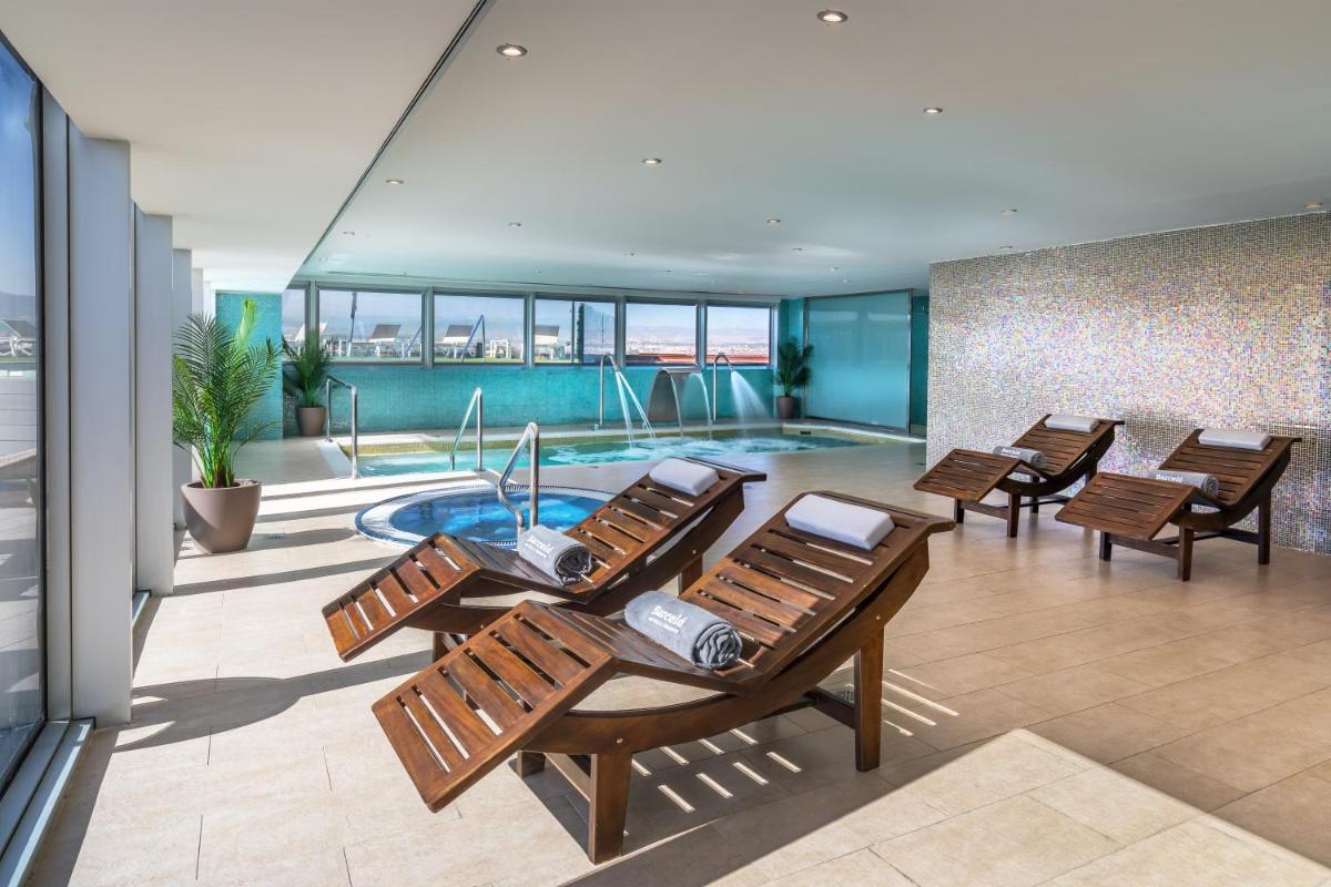 un grupo de sillas y una piscina en un edificio en Barceló Granada Congress, en Granada