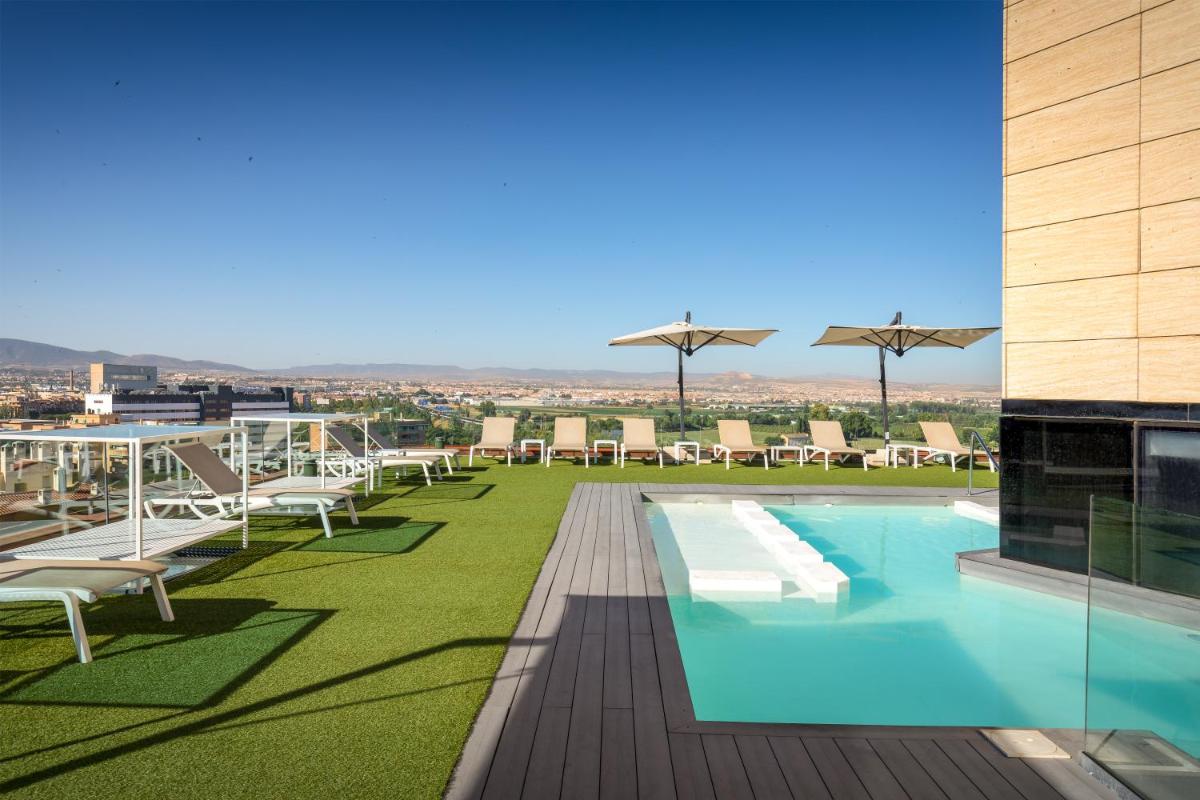 Una piscina en la azotea de un edificio con tumbonas. en Barceló Granada Congress, en Granada