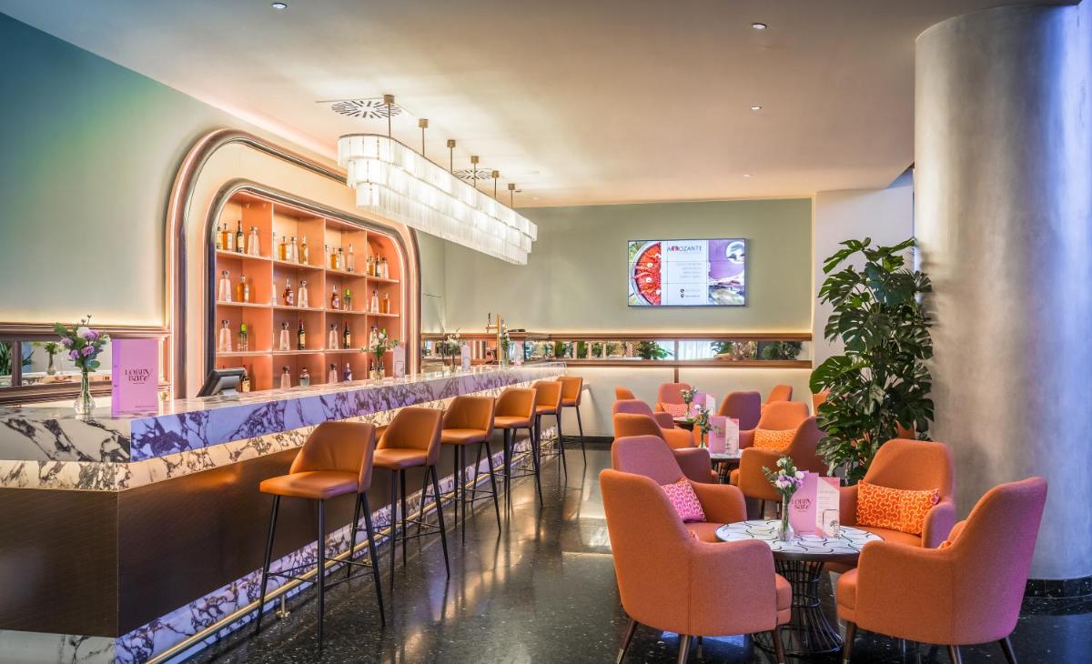 un restaurante con sillas naranjas y un bar en Barceló Granada Congress, en Granada