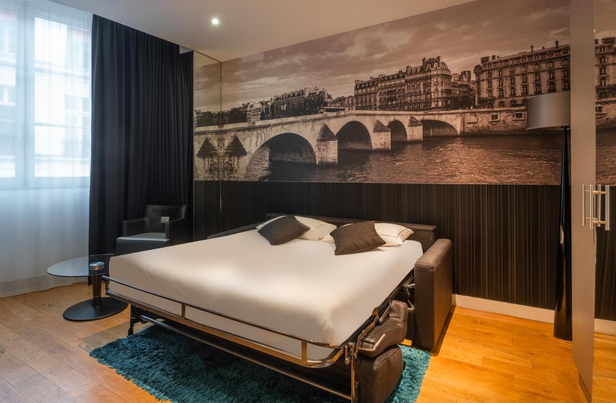 une chambre avec un lit et un tableau représentant un pont dans l'établissement L'Empire Paris - Louvre, à Paris