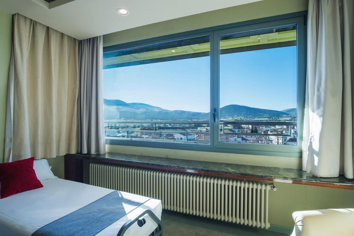 Un dormitorio con una cama y una ventana grande. en Alda Mirador del Moncayo, en Ólvega
