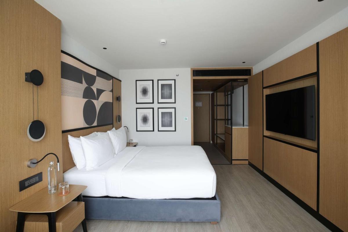 a bedroom with a large white bed and a flat screen tv at Parallel Hotel Udaipur, a member of Radisson Individuals in Udaipur