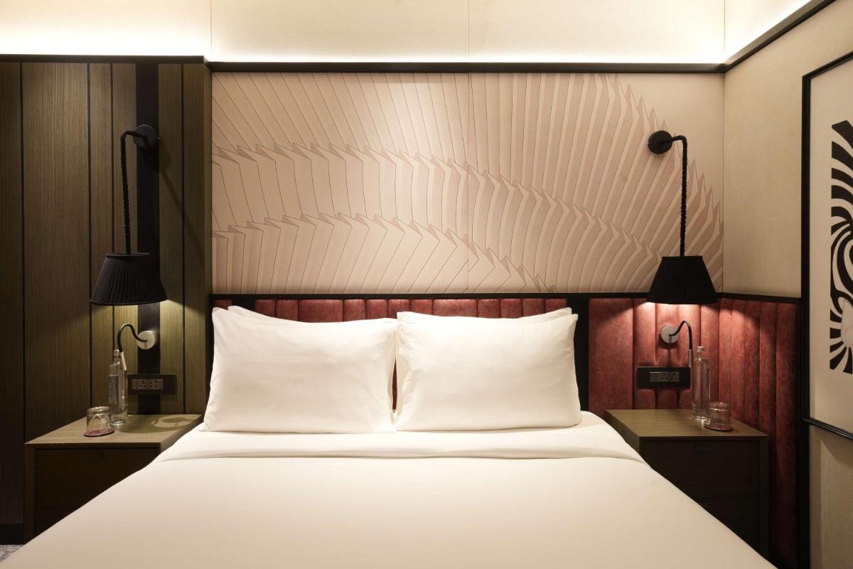 a bedroom with a bed with white sheets and two lamps at Parallel Hotel Udaipur, a member of Radisson Individuals in Udaipur