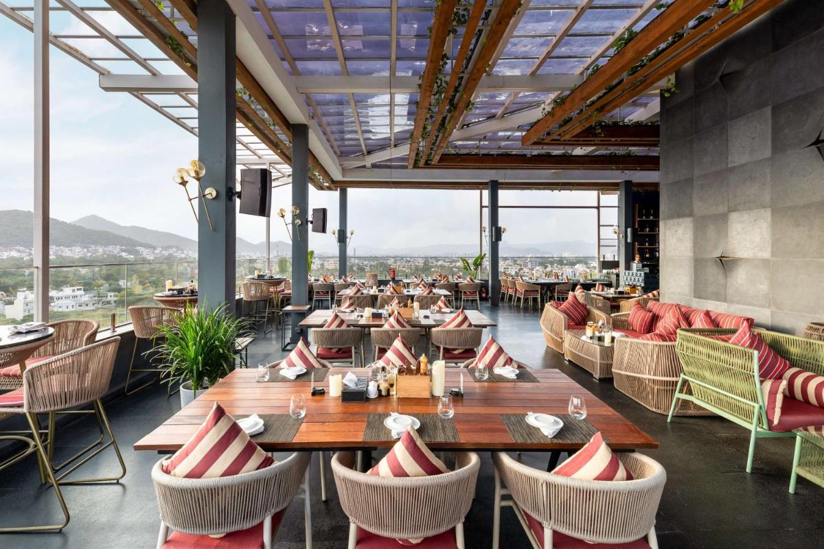 a restaurant with tables and chairs and large windows at Parallel Hotel Udaipur, a member of Radisson Individuals in Udaipur