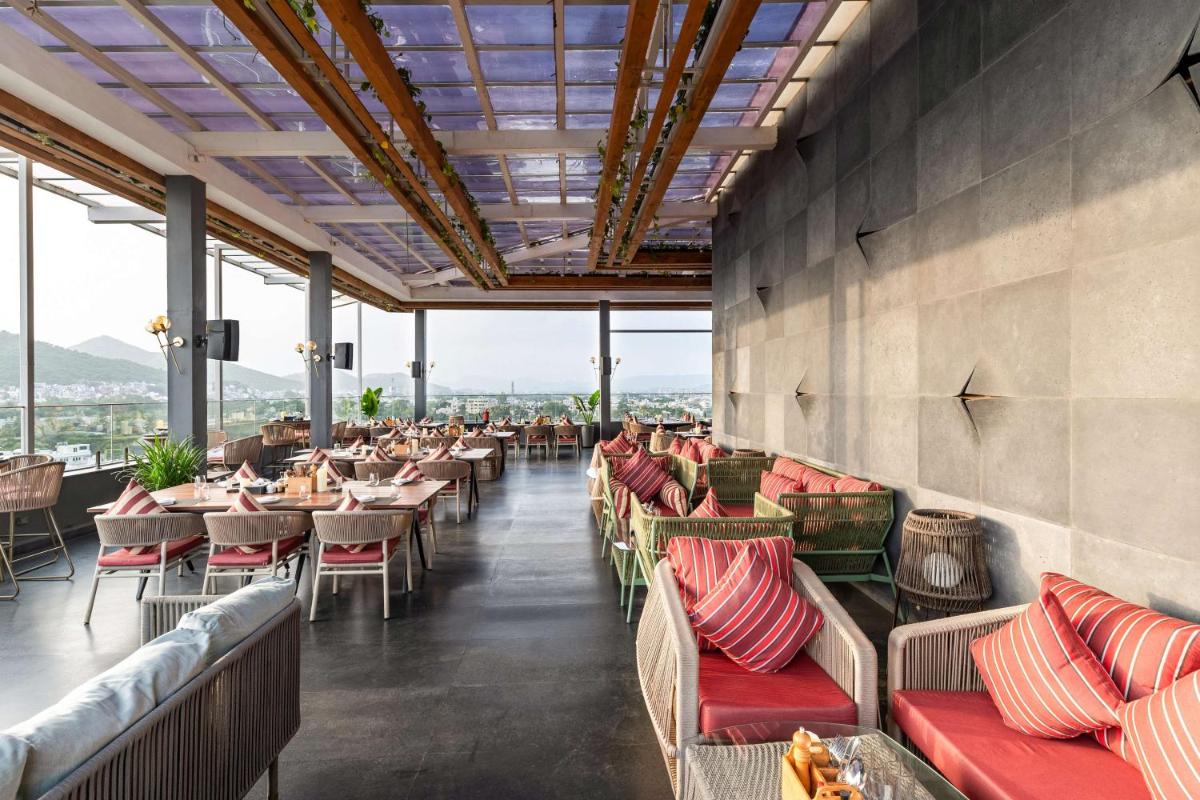 a restaurant with couches and tables and windows at Parallel Hotel Udaipur, a member of Radisson Individuals in Udaipur