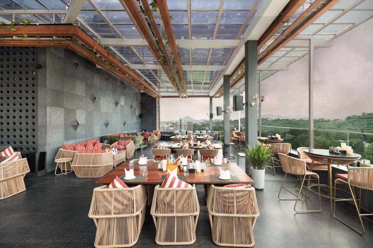 a restaurant with tables and chairs with a view at Parallel Hotel Udaipur, a member of Radisson Individuals in Udaipur